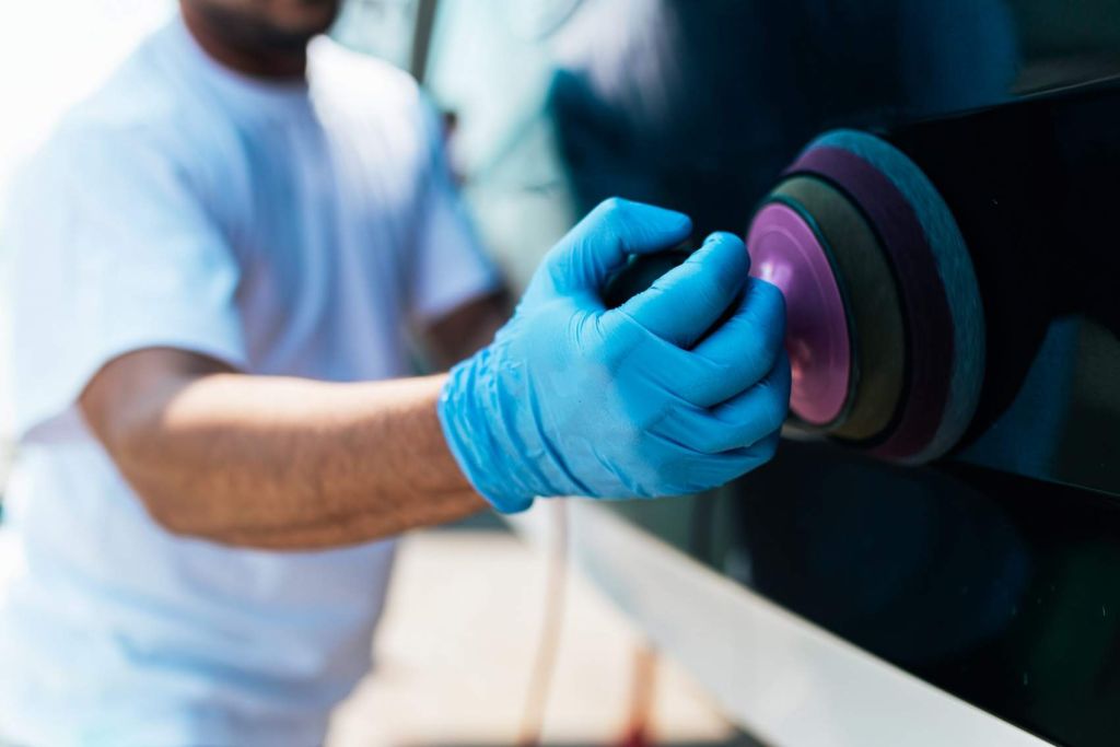 Boat maintenance - Man with orbital polisher polishing boat in marina. Selective focus.